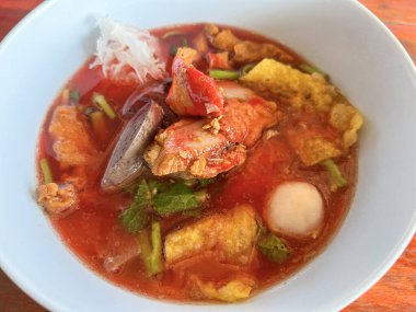 Food Thai style noodle with assorted tofu and fish ball in red soup - Asian food style pink seafood flat noodles on soup bowl 