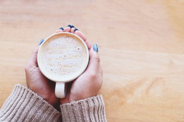 coffee caramel woman coffee with hand holding a cup on the wood table, caramel coffee cup in the morning - hot caramel macchiato - top view