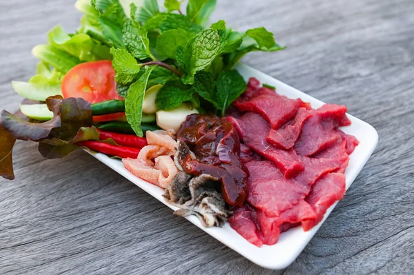 raw beef meat cuts slices on white plate and fresh vegetables fresh meat top view - beef sashimi , beef liver asian thai food