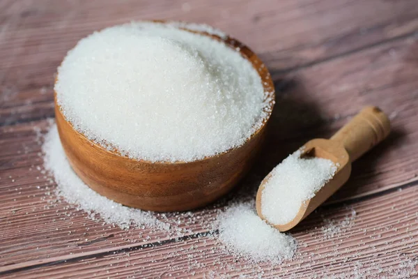 Sugar on spoon and wooden bowl, white sugar for food and sweets dessert candy heap of sweet sugar crystalline granulated