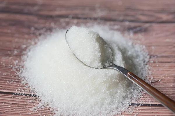 Sugar on spoon and wooden background, white sugar for food and sweets dessert candy heap of sweet sugar crystalline granulated