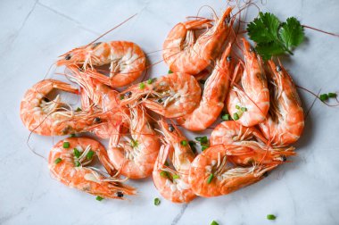 Beyaz tabakta karides arka planda yemek masası yiyecekler, taze karidesler karidesler limonlu otlar ve baharatlı deniz mahsulleri, üst manzara.