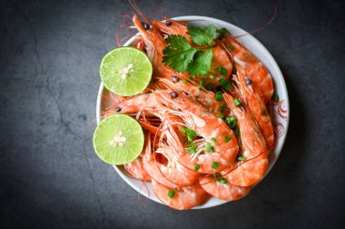 Taze karidesler, limonlu deniz ürünleri, baharatlı limon, karides ve ahşap arka plan yemek masası.