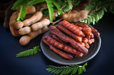 Tamarind yemek için tatlı olgun tamarinds koyu plaka arka planda, Tamarind tropikal meyve kabuğu yaz