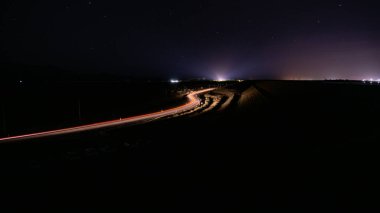 Gece vakti dolambaçlı bir yolda ışık izlerini güzel bir şekilde yakalayan nefes kesici uzun pozlama fotoğrafı.
