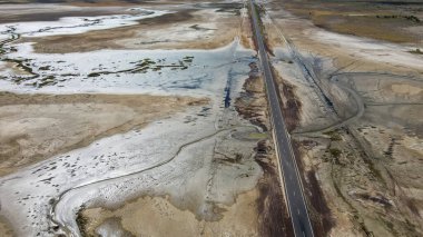 An expansive aerial view showcases a vast marshland, featuring winding streams and captivating cloud formations clipart