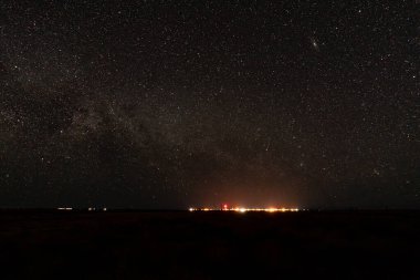 The vast night sky is adorned with countless sparkling stars shining brightly over the bustling city below, creating an enchanting scene clipart