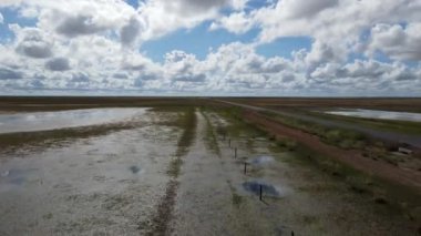 Sulak alanların sakin manzarası, yukarıdaki bulutları yansıtıyor, güzellikleri ve sükuneti gözler önüne seriyor.