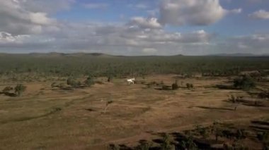 Bir hava çekimi, dinamik ve bulutlu bir gökyüzüne karşı geniş ve geniş yeşil bir manzara sergiliyor. Fantom 3 etrafında yörüngeler. 