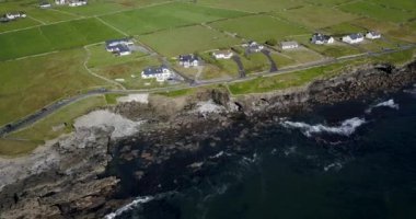 Bir hava görüntüsü çarpıcı bir kıyı manzarasını gözler önüne seriyor. Canlı yeşil tarlaları ve tuhaf deniz kenarlı evleri var.