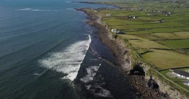 Sersemletici hava görüntüsü, canlı yeşil tarlaların yanında kayalık kıyılara çarpan çok güzel dalgalar.