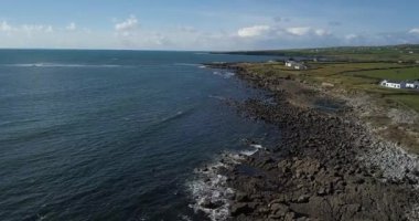 Çarpıcı bir sahil manzarası sakin suları olan kayalık bir kıyıya ve birkaç bulutlu açık mavi bir gökyüzüne sahiptir.