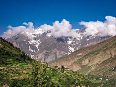 Karla kaplı dağlar, mavi gökyüzünde beyaz bulutlar Leh 'e doğru yol alıyor..