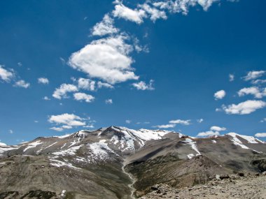 Karla kaplı dağlar, mavi gökyüzünde beyaz bulutlar Leh 'e doğru yol alıyor..