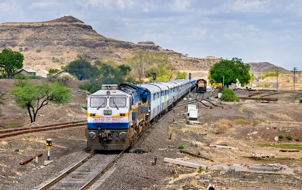 Daundaj, Maharashtra, Hindistan-3 Haziran 2017: Hindistan Demiryolları hızlı ekspres treni küçük bir istasyonda bir yolcu trenini geçiyor .