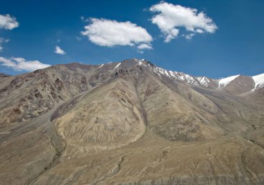 Diskit 'e giden Nubra Vadisi' nde mavi gökyüzü arka planında beyaz bulutlu büyük dağlar.