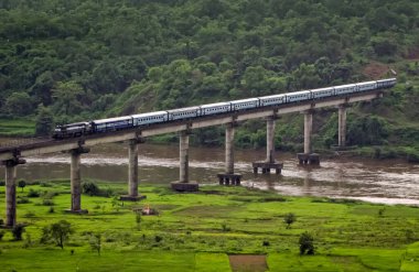 Süper hızlı Janshatabdi ekspres treni, tepeden geçen bir tünelden çıkıyor ve Sangameshwar, Maharashtra, Hindistan 'daki uzun bir köprüden geçiyor..