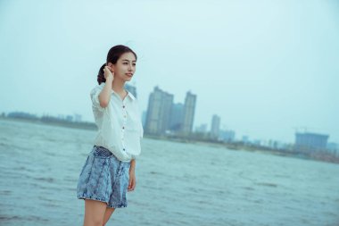 Beyaz elbiseli bir kız gölün kenarında duruyor.