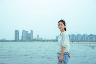 Beyaz elbiseli bir kız gölün kenarında duruyor.