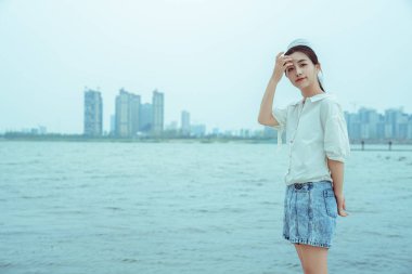 Beyaz elbiseli bir kız gölün kenarında duruyor.