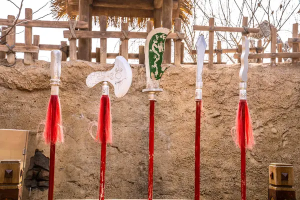 Stock image This image showcases various ancient Chinese weapons, including swords, axes, and halberds, hanging in front of a wall, highlighting the charm of traditional culture.