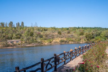 This photo was taken at Red Stone Forest, Fuxi Mountain, Xinmi, Henan, showcasing a tranquil lake and the surrounding natural scenery. clipart