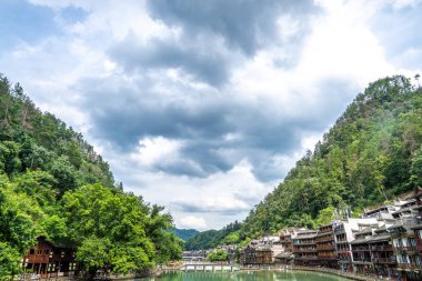 Bu resim, Hunan Xiangxi 'deki Fenghuang Antik Kasabası' nın geleneksel Miao mimarisini ve dağlık manzarasını sergiliyor.