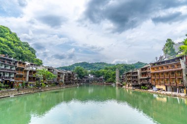 Bu resim, Hunan Xiangxi 'deki Fenghuang Antik Kasabası' nın geleneksel Miao mimarisini ve dağlık manzarasını sergiliyor.