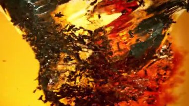 Portakal Arkaplanındaki Su Fırıldağında Siyah Çayı Sızdıran Süper Yavaş Film Çekimi. 4K 'da Yüksek Hız Sinema Kamerası ile çekildi..