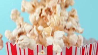 Mavi arka planda süper yavaş çekimde patlamış mısır düşüyor. 1000Fps 4K 'de yüksek hızlı sinema kamerasıyla çekildi..