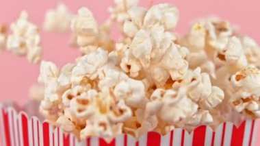 Patlamış mısırı pembe arka planda yavaş çekimde düşürmek. 1000Fps 4K 'de yüksek hızlı sinema kamerasıyla çekildi..