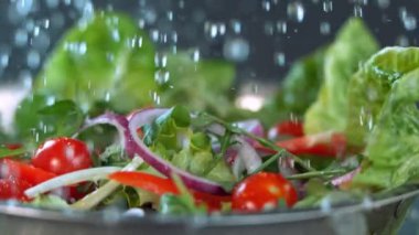 Su, süper yavaş çekimde taze salataya dökülüyor. 4K 'de yüksek hızlı sinema kamerasıyla çekiliyor..