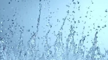 Süper Yavaş Çekim Soyut Su Sıçratma Çekimi açık mavi arka planda, 300 fite ayarlandı. 4K Çözünürlükte Yüksek Hız Sinema Kamerası ile Çekim.