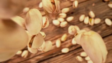 Taze kavrulmuş Pistachio Fıstığı Süper Yavaş Çekimi Tahta Masa 'ya 1000 fps hızla düşüyor. 4K 'da Yüksek Hız Sinema Kamerasında Çekim.