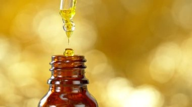 Yağ esansının Süper Yavaş Çekimi 600fps 'de Altın Arka plan' daki Şişe 'ye Düşür. 4K 'da Yüksek Hız Sinema Kamerası ile çekildi..