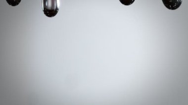 Koyu Gri Arkaplan 'a 1000 fps hızla Yağlı Sıvı damlatan Süper Yavaş Makro Çekim. 4K 'da Yüksek Hız Sinema Kamerası ile çekildi.