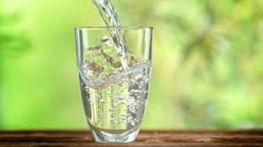 Super Slow Motion Shot of Pouring Pure Water into Glass on Green Natural Background at 1000fps. Filmed with High Speed Cinema Camera in 4k.