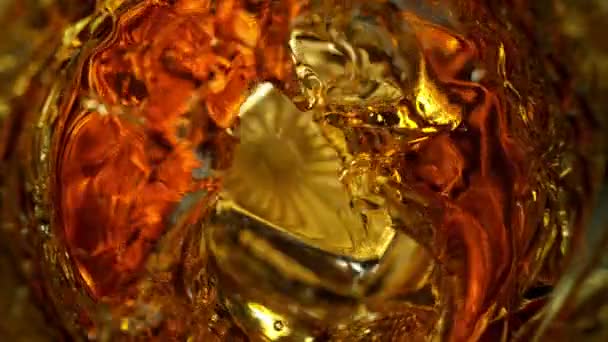 超スローモーション詳細1000Fpsでゴールデンアルコール液でガラスに落ちるアイスキューブのショット 4Kで高速シネマカメラで撮影 — ストック動画