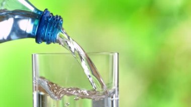 Super Slow Motion Detail Shot of Pouring Pure Water into Glass on Green Background at 1000fps. Filmed with High Speed Cinema Camera in 4k.