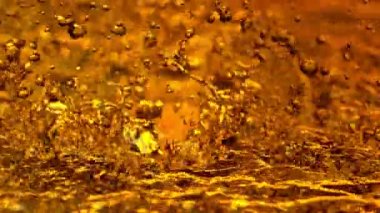 Super Slow Motion Shot of Splashing Dark Golden Liquid Background at 1000fps. Filmed with High Speed Cinema Camera in 4K Resolution.