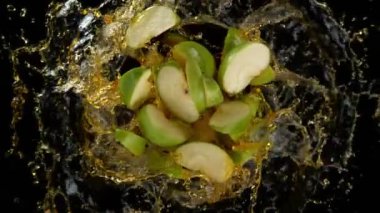 Patlayan yeşil elma kesiklerinin ve siyaha 1000 fitte sıçrayan sıvının süper yavaş çekimi. Yüksek hızlı sinema kamerasıyla çekilmiş..