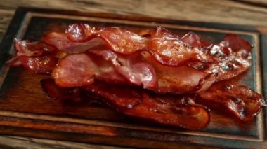 Super Slow Motion Shot of Roasted Bacon Slices Falling on Wooden Board at 1000 fps. Filmed with High Speed Cinema Camera in 4K Resolution.