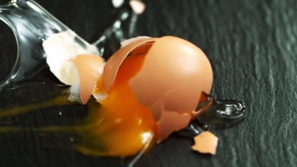 Super Slow Motion Shot Falling Breaking Whole Egg Black Table — Vídeo de Stock