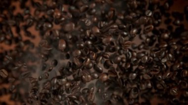 Super Slow Motion Shot of Coffee Beans and Smoke Flying Towards Camera on Brown Background at 1000fps. Filmed with High Speed Cinema Camera in 4k.