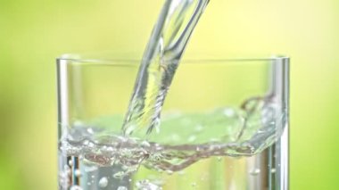 Super Slow Motion Detail Shot of Pouring Pure Water into Glass on Green Background at 1000fps. Filmed with High Speed Cinema Camera in 4k.