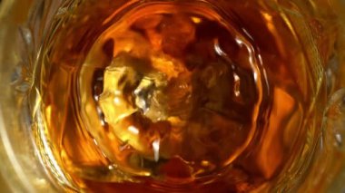 Super Slow Motion Detail Shot of Drop Falling into Glass with Whiskey and Ice Cubes at 1000fps. Filmed with High Speed Cinema Camera at 4K.