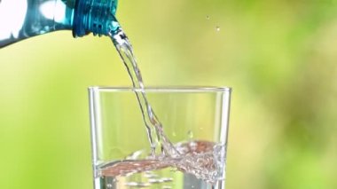 Super Slow Motion Detail Shot of Pouring Pure Water into Glass on Green Background at 1000fps. Filmed with High Speed Cinema Camera in 4k.