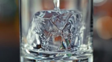 Super Slow Motion Detail Shot of Pouring Vodka into Glass With Perfect Ice Cube at 1000fps. Filmed with High Speed Cinema Camera, 4K.