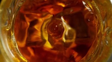 Super Slow Motion Detail Shot of Drop Falling into Glass with Whiskey and Ice Cubes at 1000fps. Filmed with High Speed Cinema Camera at 4K.