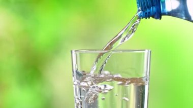 Super Slow Motion Detail Shot of Pouring Pure Water into Glass on Green Background at 1000fps. Filmed with High Speed Cinema Camera in 4k.
